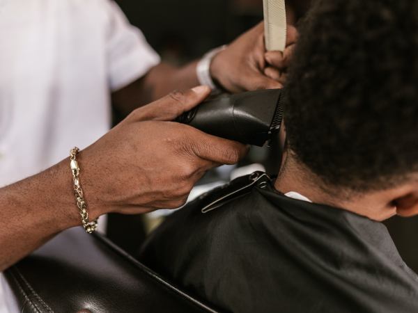 A person cutting a second person's hair with clippers